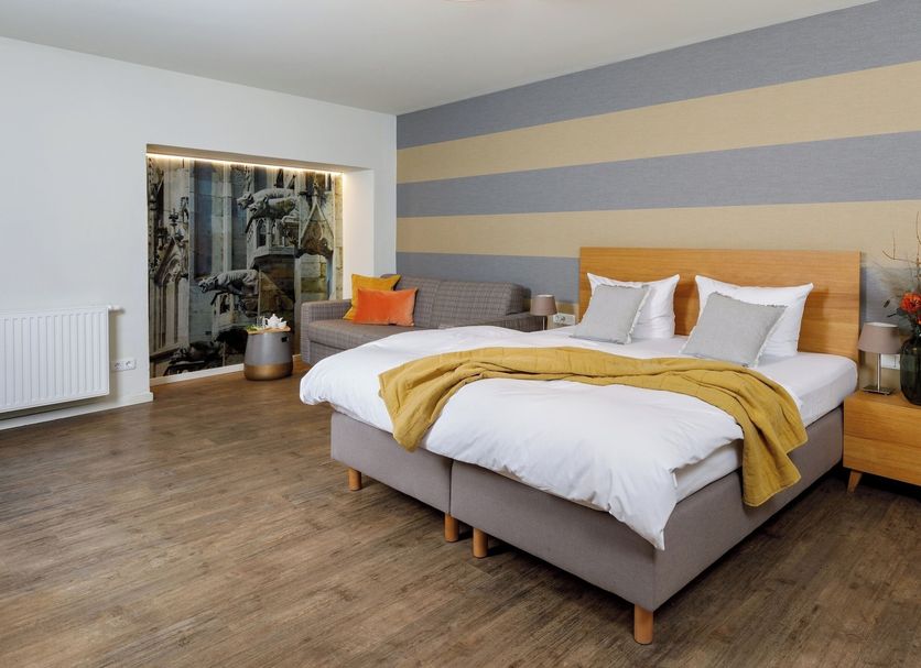Hotel am Peterstor in Regensburg bedroom with king bed, striped accent wall, and wood flooring