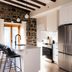 Maison Place Royale by Luxury In Transit in Montreal kitchen with stone wall, island seating and stainless steel appliances