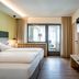 Hotel Klingler in Maurach guest room with twin beds, balcony door, wall-mounted TV, and seating nook