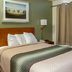HomeTowne Studios by Red Roof Salem, OR guest room with bed, wall art, lamp and curtained window