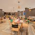 Ginger Jaipur dining area with wooden tables, chairs, pendant lights and large windows