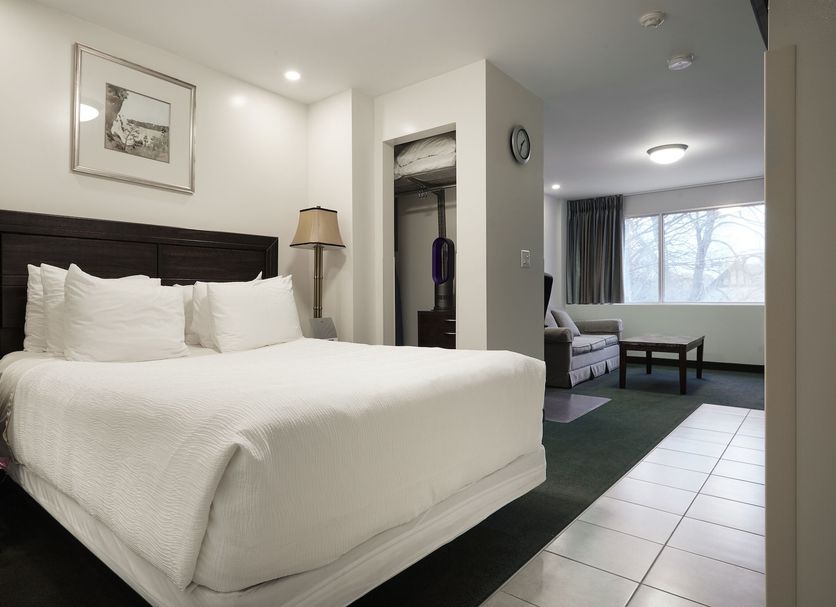 The Business Inn Ottawa guest room with king bed, lounge seating, and city-view window