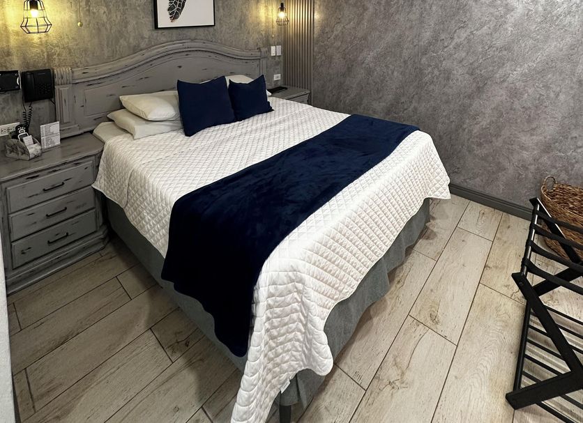 Berlor Airport Inn in Alajuela guest room with queen bed, bedside lamps, wall art, and air conditioner