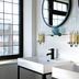 The Relais Cooden Beach bathroom with double sinks, round mirrors, and large windows in Bexhill-on-Sea