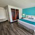 Howard Johnson by Wyndham Woodstock NB guest room with king bed, teal accent wall and modern art