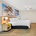 Days Inn by Wyndham Jacksonville NC guest room with king bed, beach artwork, desk and TV