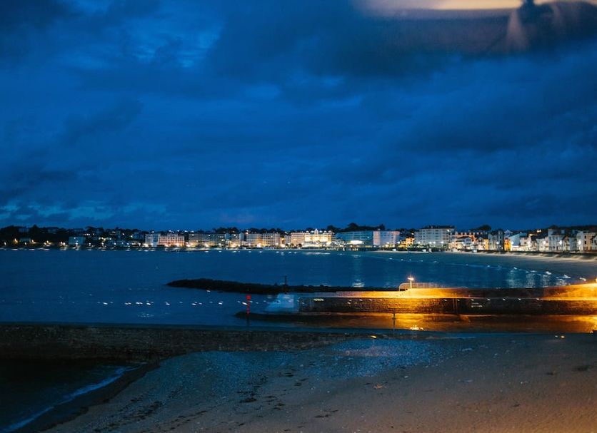 Hôtel La Caravelle in Ciboure with nighttime bay view, lit shoreline and sandy beach
