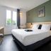 City Résidence Paris Saint-Maurice room with queen bed, desk, window and green accent wall in Saint-Maurice
