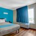 Motel 6 Raleigh North guest room with bed, blue accent wall, window, and air conditioner in Raleigh
