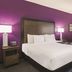 La Quinta Inn & Suites by Wyndham Virginia Beach guest room with king bed, purple accent wall, and yellow chair