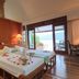 Badian Island Wellness Resort bedroom with flower-covered bed and ocean view through open doors in Badian