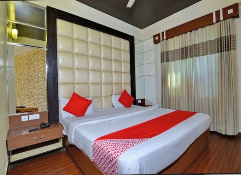 Hotel aroma classic Jaipur guest room with king bed, red accents, wood flooring, and window drapes