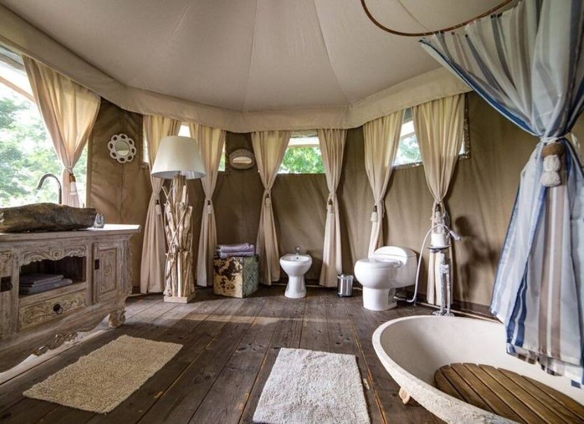 Glamping Canonici di San Marco in Mirano: luxury tent bathroom with bathtub, toilet, sink and wood floors