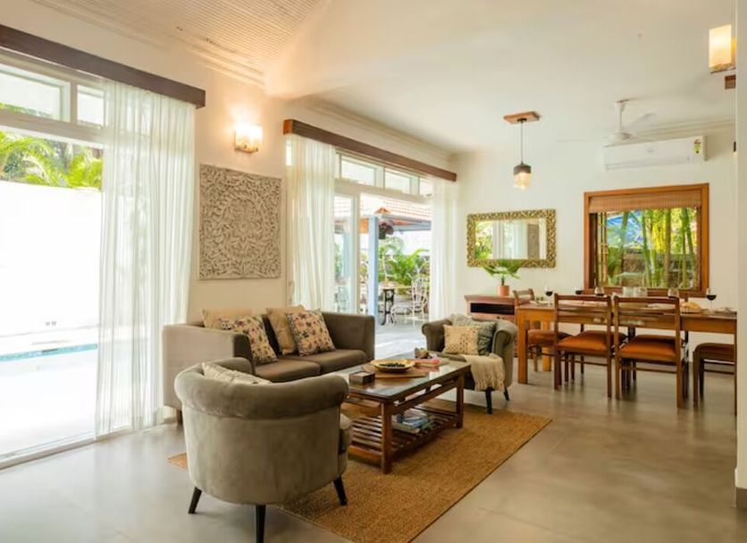 Aguada Anchorage - The Villa Resort in Panaji living area with sofa, coffee table, dining space and patio view