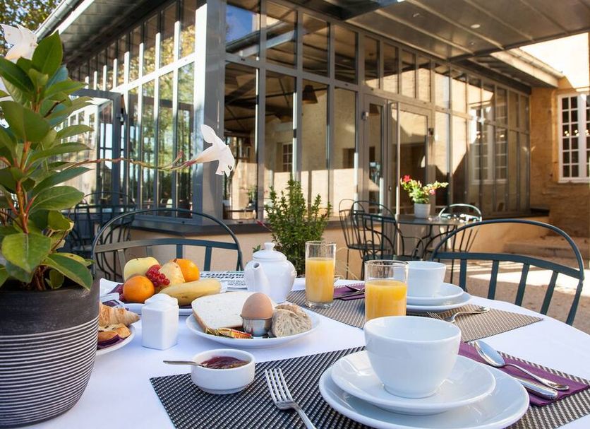 Breakfast table on the terrace at Hôtel La Hoirie in Sarlat-la-Canéda with juice, cups and pastries