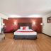 OYO Hotel Mcallen Airport South room with king bed, red accent wall, chair and floor lamp in McAllen