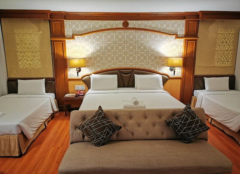 Sakol Hotel in Hat Yai guest room with three beds and a seating bench