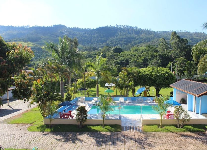 Pousada Vale da Montanha in Serra Negra with outdoor pool, palm trees, and mountain views
