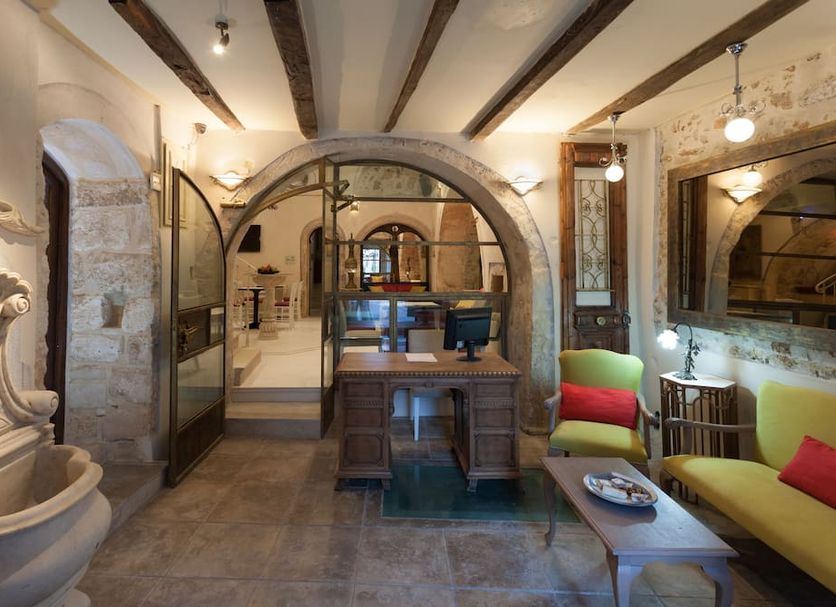Hamam Oriental Suites in Rethymno: elegant suite with stone arches, desk, sofa, and ornate sink