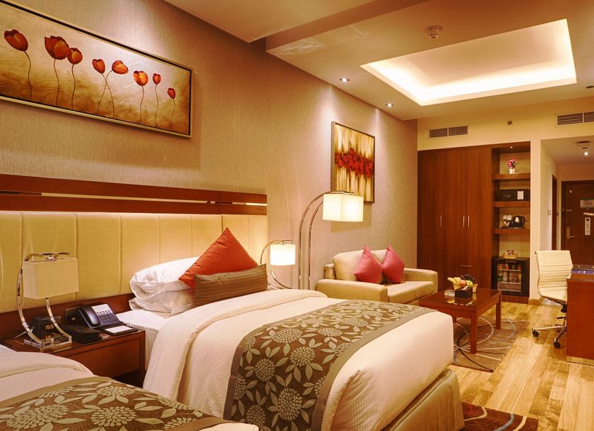 Rose Park Hotel Al Barsha, Dubai guest room with twin beds, seating area, and warm wood accents