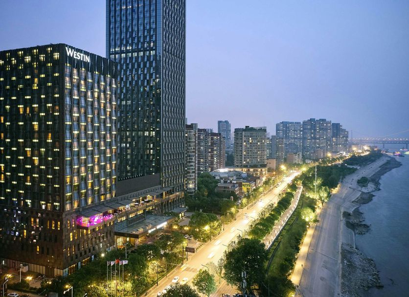 The Westin Wuhan Wuchang hotel with illuminated towers and riverfront city skyline in Wuhan