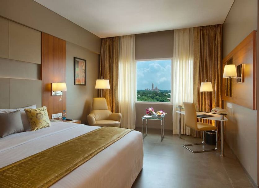 Royal Orchid Central Vadodara guest room with city view, bed, armchair, desk and window seating