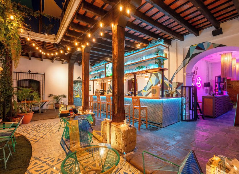 Adra Hostel in Antigua courtyard lounge with string lights, patterned floor, and colorful bar seating