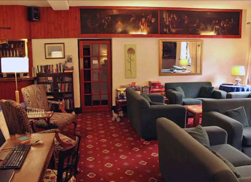 Gairloch Highland Lodge lounge in Gairloch with sofas, armchairs, bookshelves and red patterned carpet