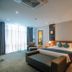 Petro Hotel in Vung Tau guest room with king bed, sofa bench, bedside lamps and large window