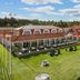 Hotel Pinenhus in Glyngøre with red-roofed buildings, Danish flags, and a lawn overlooking the water