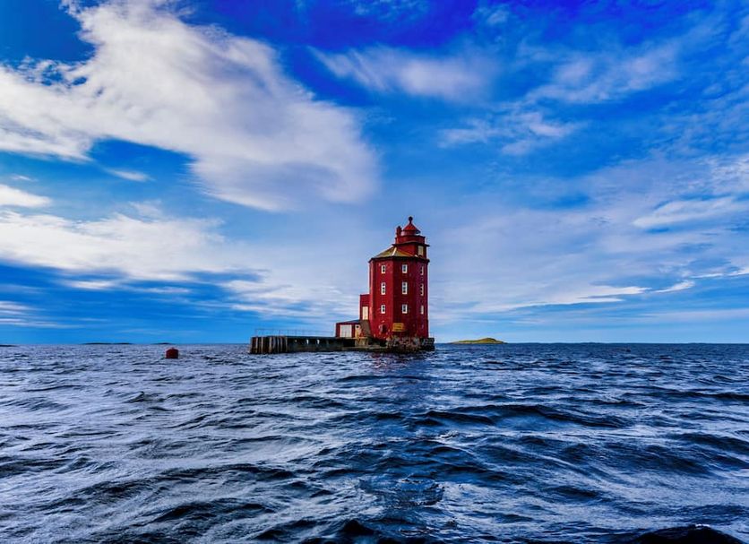 Ørland Kysthotell in Brekstad with a red lighthouse on the sea under a blue sky