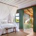 Pousada Outeiro in Trancoso bedroom with canopy bed and open doors to a tropical balcony