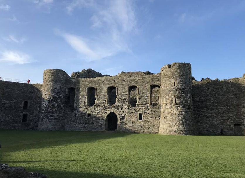 Llandudno Hostel in Llandudno with a stone castle ruin and open grassy courtyard under blue sky