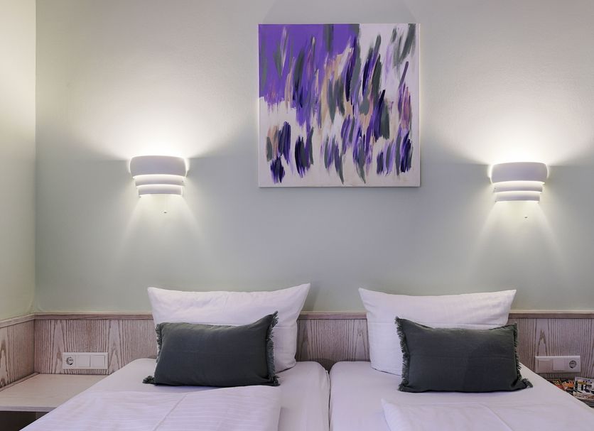 Hotel Kunterbunt in Wurzburg twin bed room with purple abstract wall art and wall lamps