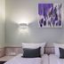 Hotel Kunterbunt in Wurzburg twin bed room with purple abstract wall art and wall lamps
