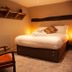 The Wiremill, Lingfield hotel room with double bed, wall shelves, armchair and soft lighting
