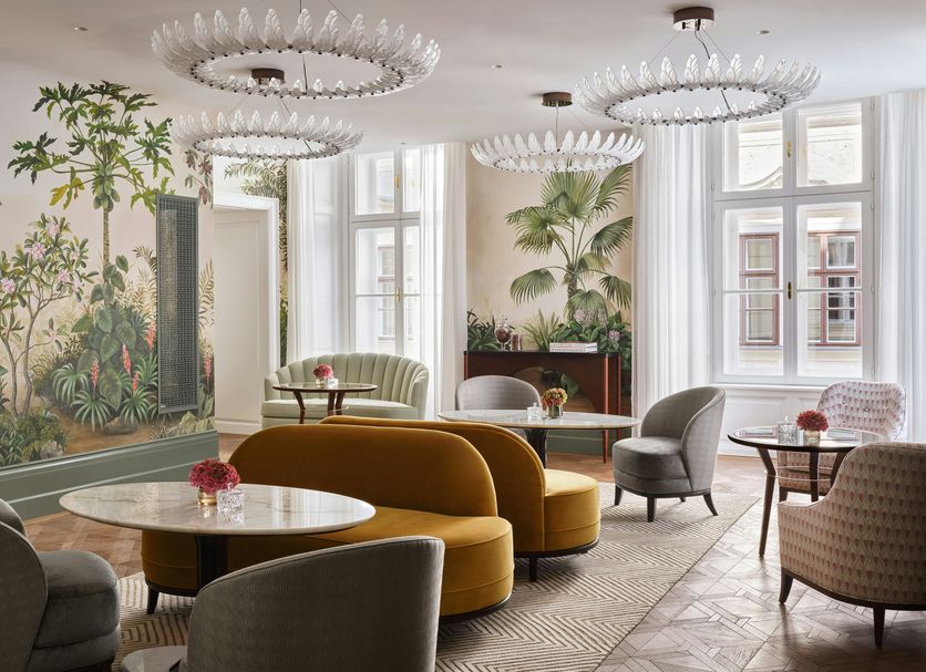 Rosewood Vienna in Vienna lounge with curved sofas, palm murals, and crystal chandeliers
