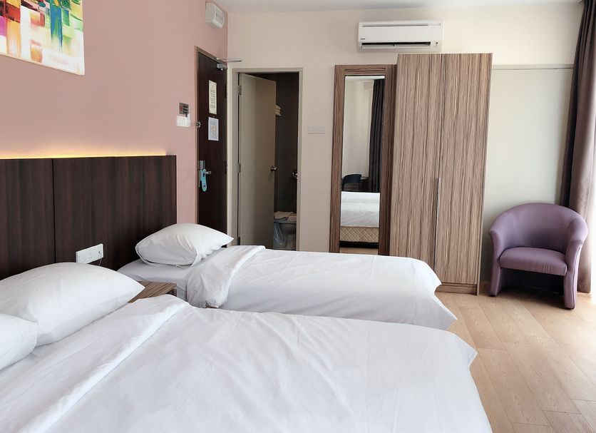 Tumike Hotel Bentong room with two single beds, wardrobe, chair, and air conditioner in Bentong
