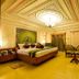 Hotel Ambica Empire Chennai ornate suite with king bed, chandelier, seating area and mirrored wall
