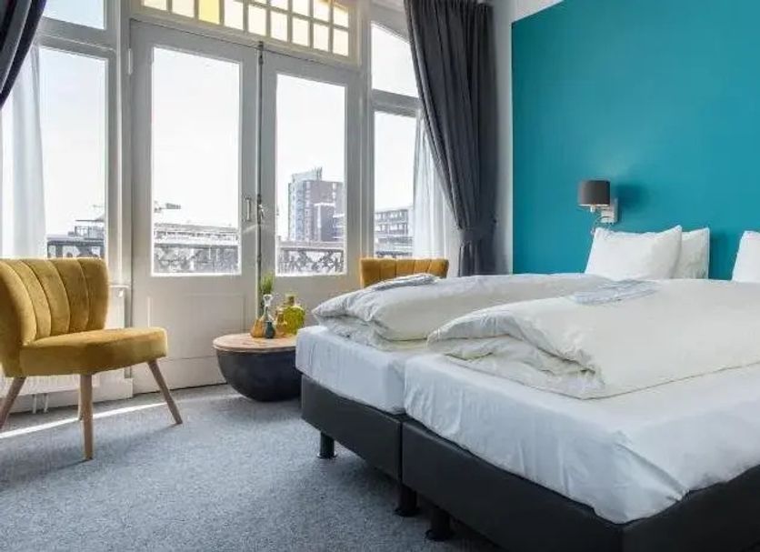 Villahotel Vlissingen room with teal accent wall, bed, and city view through large windows in Vlissingen