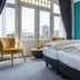 Villahotel Vlissingen room with teal accent wall, bed, and city view through large windows in Vlissingen
