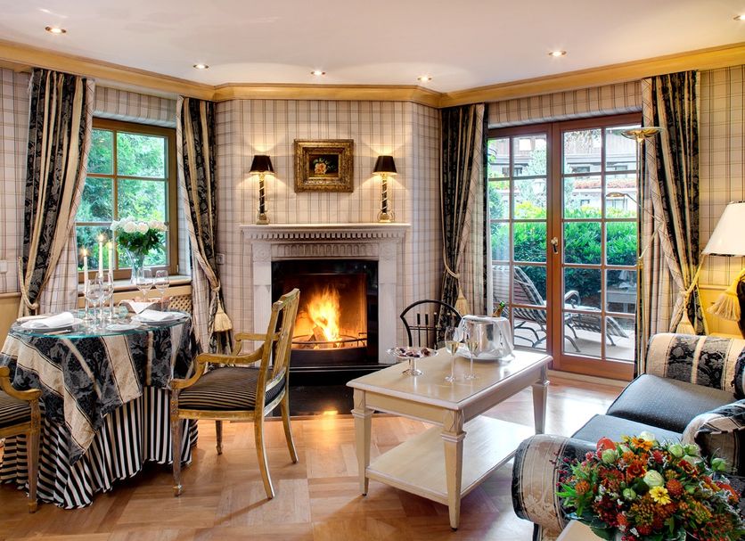 Hotel Bareiss in Baiersbronn lounge with fireplace, dining table and garden-view French doors