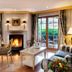 Hotel Bareiss in Baiersbronn lounge with fireplace, dining table and garden-view French doors