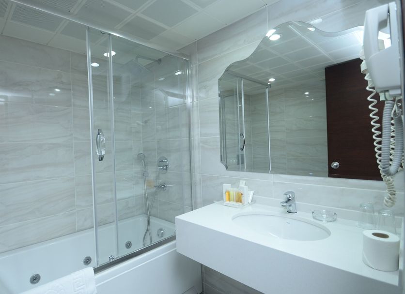 Kaya Prestige Izmir bathroom with glass shower, bathtub, and white vanity with mirror