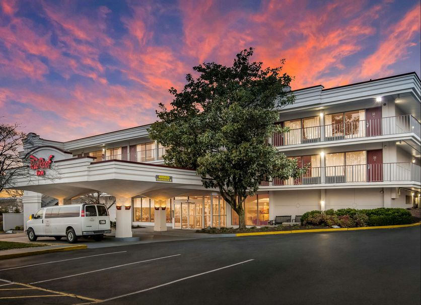Red Roof Inn Baltimore South - Glen Burnie exterior at dusk with pink sky, covered entrance and van