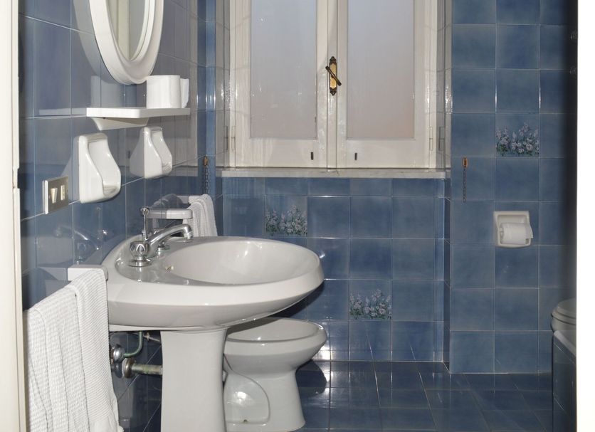 Hotel Polito in Forio bathroom with pedestal sink, toilet, mirror and blue tiled walls