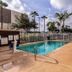 Studio 6 McAllen TX outdoor pool with lounge chairs and palm trees under a partly cloudy sky
