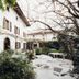 Ristolocanda Grani di Pepe in Flaibano with a leafy courtyard, stone walkway, and white facade