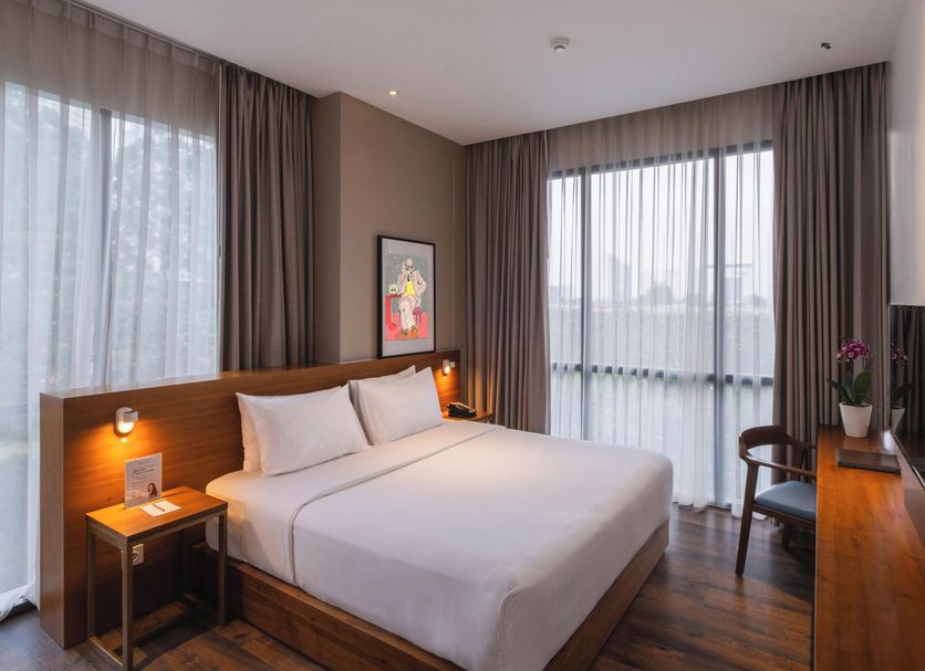 Veranda Serviced Residence Puri Jakarta guest room with king bed, floor-to-ceiling windows, and wood desk