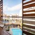 Balcony at Alegria Plaza Paris in Lloret de Mar with wicker chairs overlooking a pool and city view